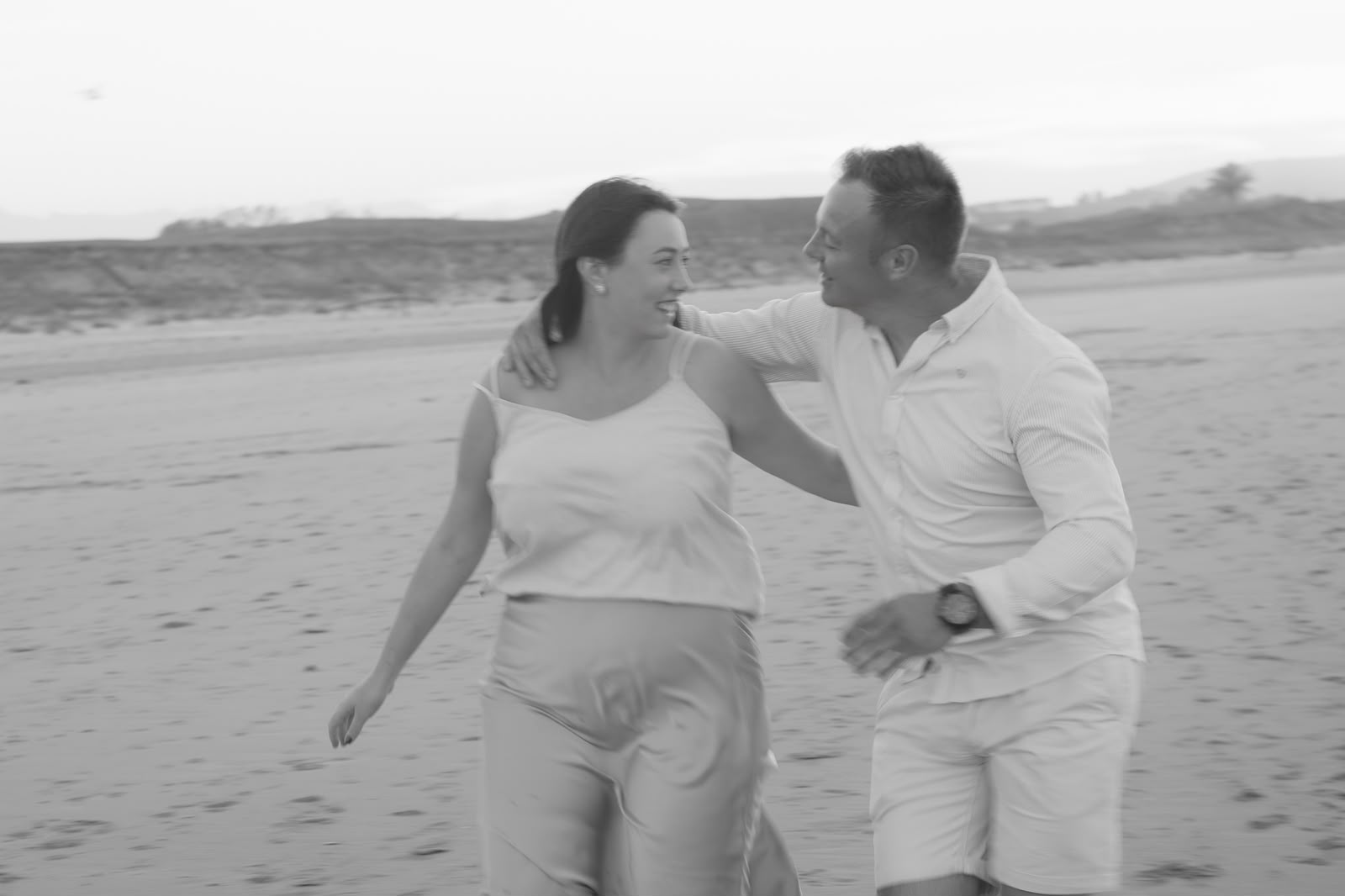 Bruno y Claudia riendo y paseando abrazados por la playa